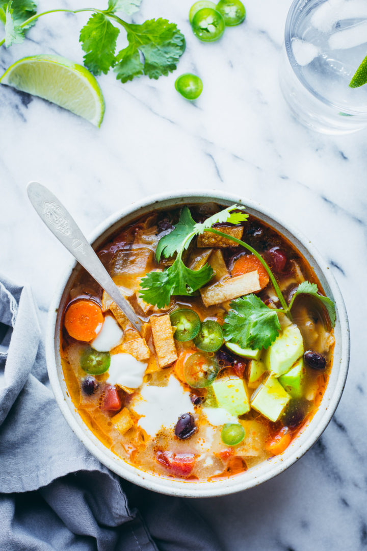 Tortilla Soup - You will love this spicy, smokey, flavorful soup topped with buttery avocado, crisp tortilla strips, fresh cilantro and citrusy lime. This easy soup makes a quick and delicious dinner. #tortilla #soup #vegan #vegetarian #glutenfree #easy #healthy #onepot #dinner #recipe #tasteloveandnourish