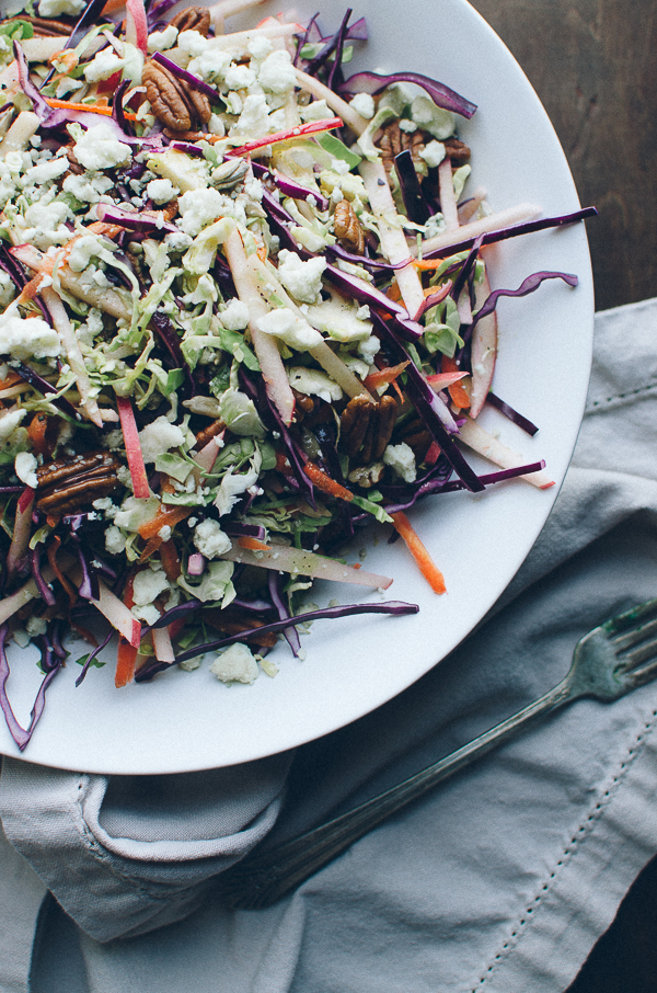This crunchy Red Cabbage and Brussels Sprouts Slaw is my family's favorite salad! It's absolutely loaded with pecans, sunflower seeds, sweet apple slices and crumbles of blue cheese and topped with a Dijon Maple Vinaigrette. | @tasteLUVnourish