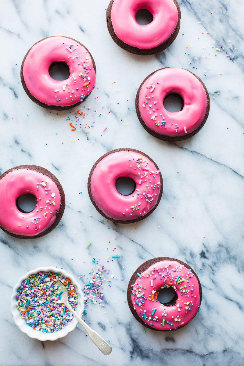 These Baked Raspberry Glazed Dark Chocolate Donuts are so much fun! The glaze is so easy to make, with fresh or frozen raspberries. Perfect for your sweetest Valentine or as a special treat anytime! From @tasteLUVnourish #donuts #doughnuts #baked #chocolate #darkchocolate #raspberry #glaze #recipe #easy #sprinkles #valentinesday #tasteloveandnourish