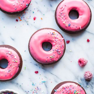 These Baked Raspberry Glazed Dark Chocolate Donuts are so much fun! The glaze is so easy to make, with fresh or frozen raspberries. Perfect for your sweetest Valentine or as a special treat anytime! From @tasteLUVnourish #donuts #doughnuts #baked #chocolate #darkchocolate #raspberry #glaze #recipe #easy #sprinkles #valentinesday #tasteloveandnourish